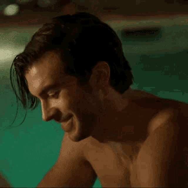 a shirtless man is standing next to a swimming pool .