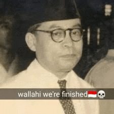 a man wearing glasses , a hat and a tie is standing in front of a skull .