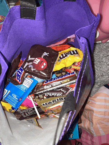 a purple bag filled with candy including hershey 's snickers and m & m 's
