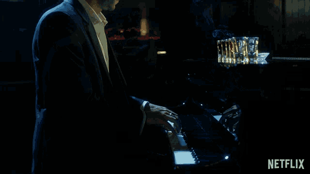 a man is playing a piano in a dark room with a netflix logo in the corner