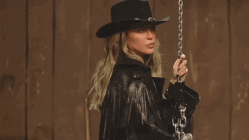 a woman wearing a cowboy hat and fringed leather jacket