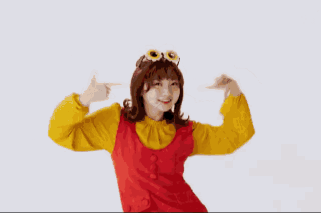 a woman in a red and yellow costume is pointing at herself with her fingers .