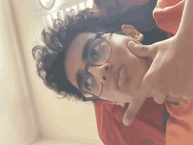 a young man wearing glasses and a red shirt is making a face
