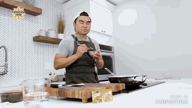 a man in an apron is standing in a kitchen holding a spoon in his hand .
