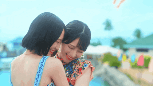 two women are hugging each other in front of a pool