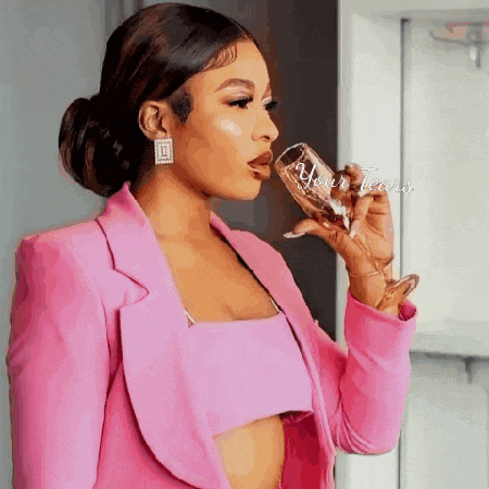 a woman in a pink suit is drinking from a wine glass .