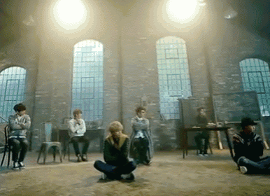 a group of people are sitting in chairs in a room with a lot of windows