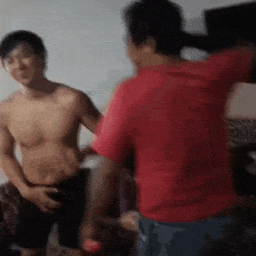 a shirtless man in a red shirt is standing next to another shirtless man .