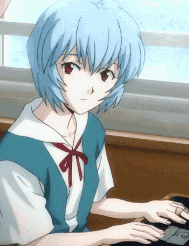 a girl with blue hair is sitting at a desk