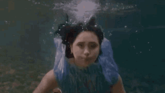 a woman in a blue dress is swimming in the ocean .