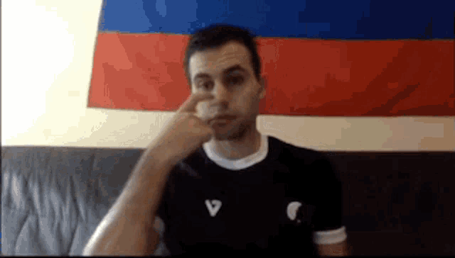 a man is sitting on a couch with his hand on his face in front of a russian flag .