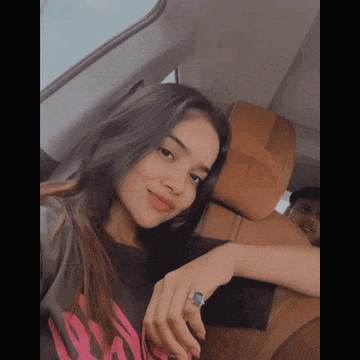 a girl is sitting in the back seat of a car with a man behind her .