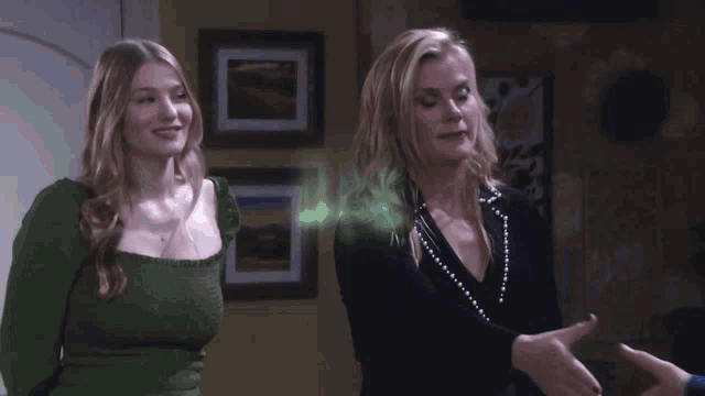 two women are standing next to each other and one of them has a green glowing object in her hair