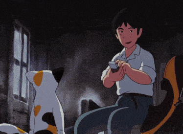 a boy is sitting next to a cat and looking at something