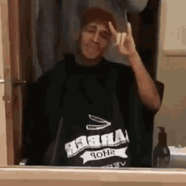 a man is making a peace sign in front of a mirror in a bathroom .