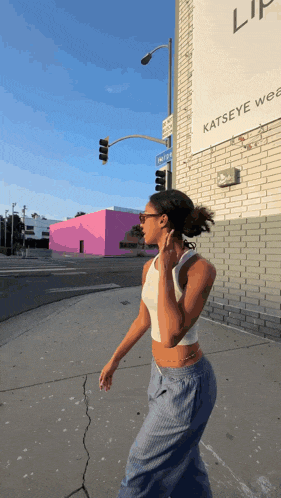 a woman is walking down a street in front of a building that says katseye
