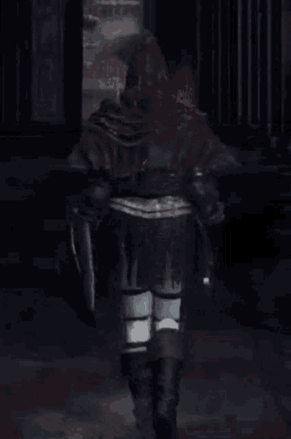 a person in armor is walking in a dark room holding a sword