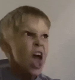 a close up of a child making a funny face with his tongue out .