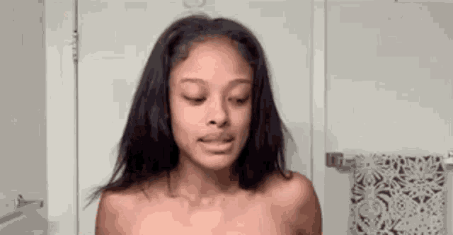 a woman without a shirt is looking at the camera in a bathroom .