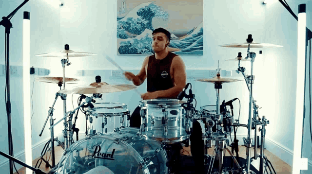 a man plays drums in front of a painting of waves