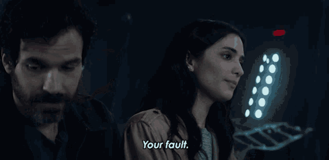 a man and a woman are standing next to each other and the woman says your fault