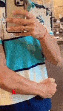 a man is taking a picture of himself in a mirror with the letter k on the bottom right