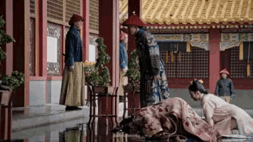 a man is kneeling down in front of a woman in a kimono in a chinese courtyard .
