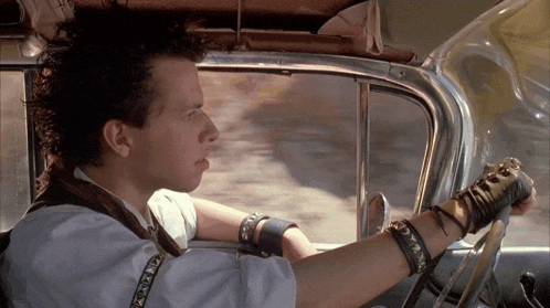 a man driving a car with a bracelet on his wrist that says ' a '