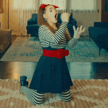 a woman singing into a microphone while kneeling on the floor