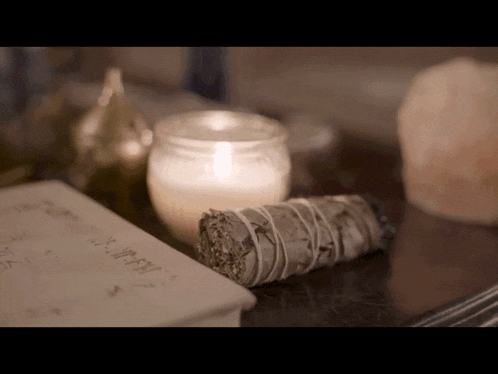 a candle and sage are on a table next to a book