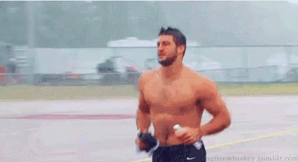 a shirtless man is running on a track while holding a glove .
