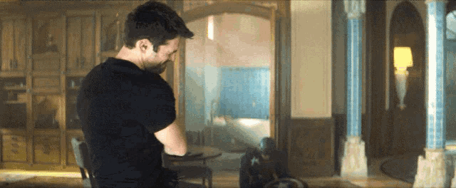 a man in a black shirt is standing in a room with columns