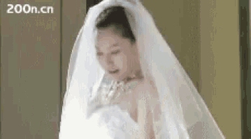 a woman in a wedding dress with a veil on her head is standing in front of a sign that says 200n.cn