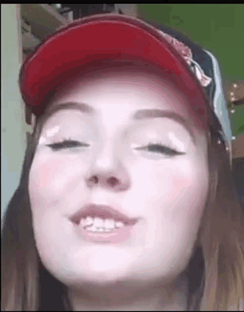 a close up of a woman wearing a red hat and white makeup .