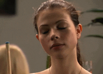 a close up of a woman 's face with a pool cue in the background .
