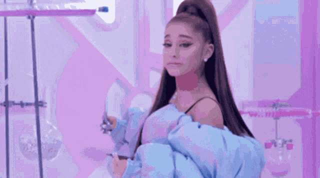 ariana grande is wearing a blue puffy jacket and a ponytail .