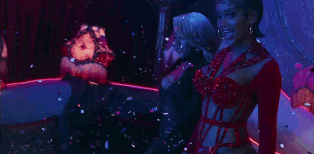 a woman in a red dress is standing in front of a bunch of money .