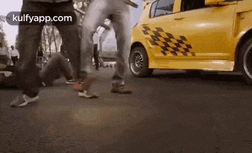 a yellow car with a checkered sticker on the side is driving down a street .
