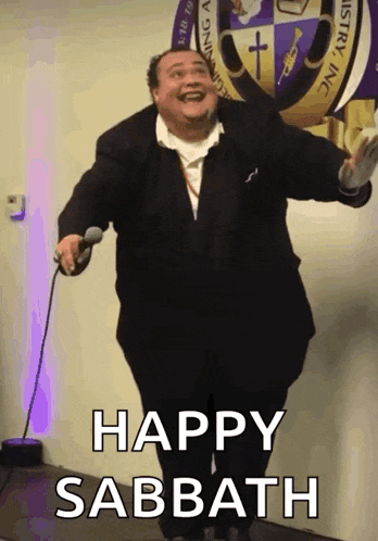 a man in a suit is holding a microphone with the words happy sabbath below him