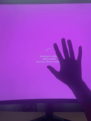 a hand is reaching out towards a purple screen that says working on updates 100 % complete