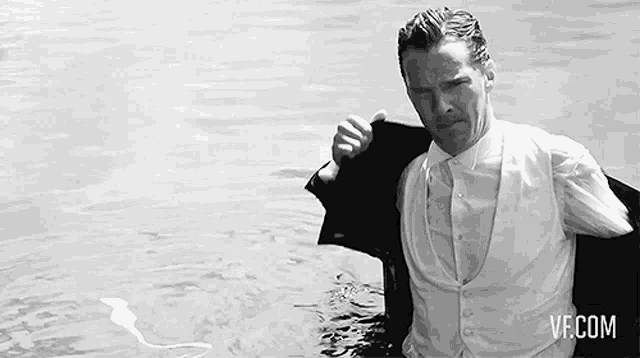 a man in a suit and vest is standing in the water .