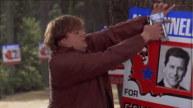a man is hanging a sign on a tree that says for