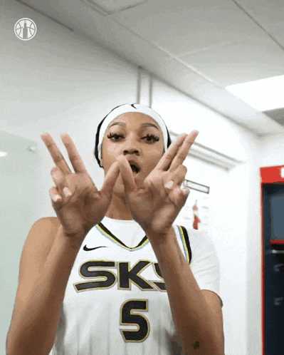 a female basketball player wearing a sky 5 jersey making a peace sign