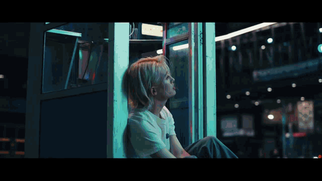 a woman sitting in a phone booth looking up at the sky
