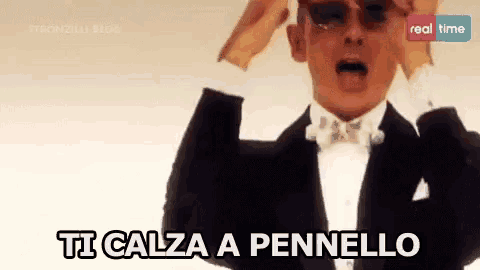 a man in a tuxedo and bow tie says ti calza a pennello .