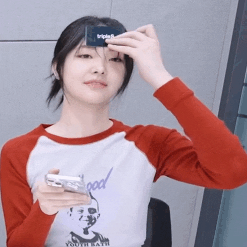 a girl wearing a shirt that says youth bath is holding a cell phone