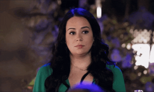 a woman wearing a green shirt looks at the camera