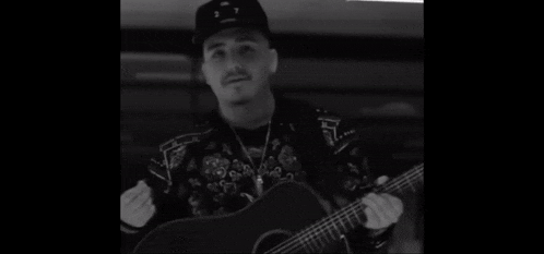 a man playing a guitar with the number 2 on his hat