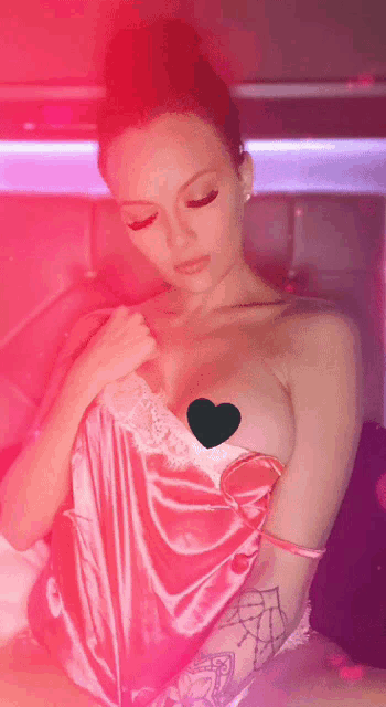 a woman in a pink dress has a green heart on her breast