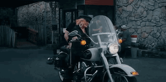 a woman is riding a motorcycle in a parking lot .